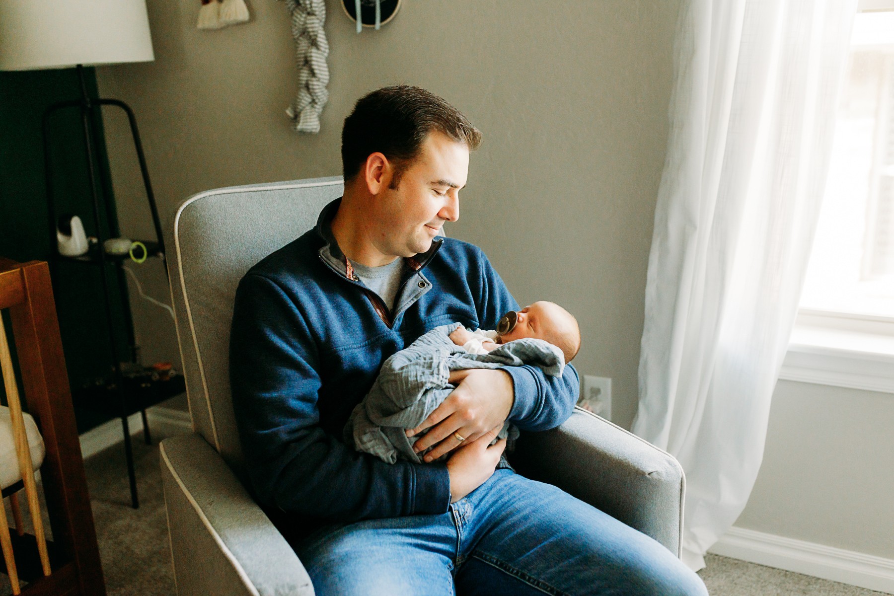 In the newborn's nursery, a dad rocks his newborn son.