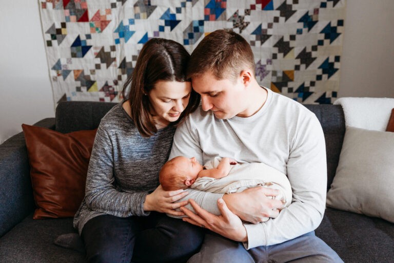 A couple sits and holds their newborn during their newborn photo session by Edmond newborn photographer Charis Elisabeth Photography.