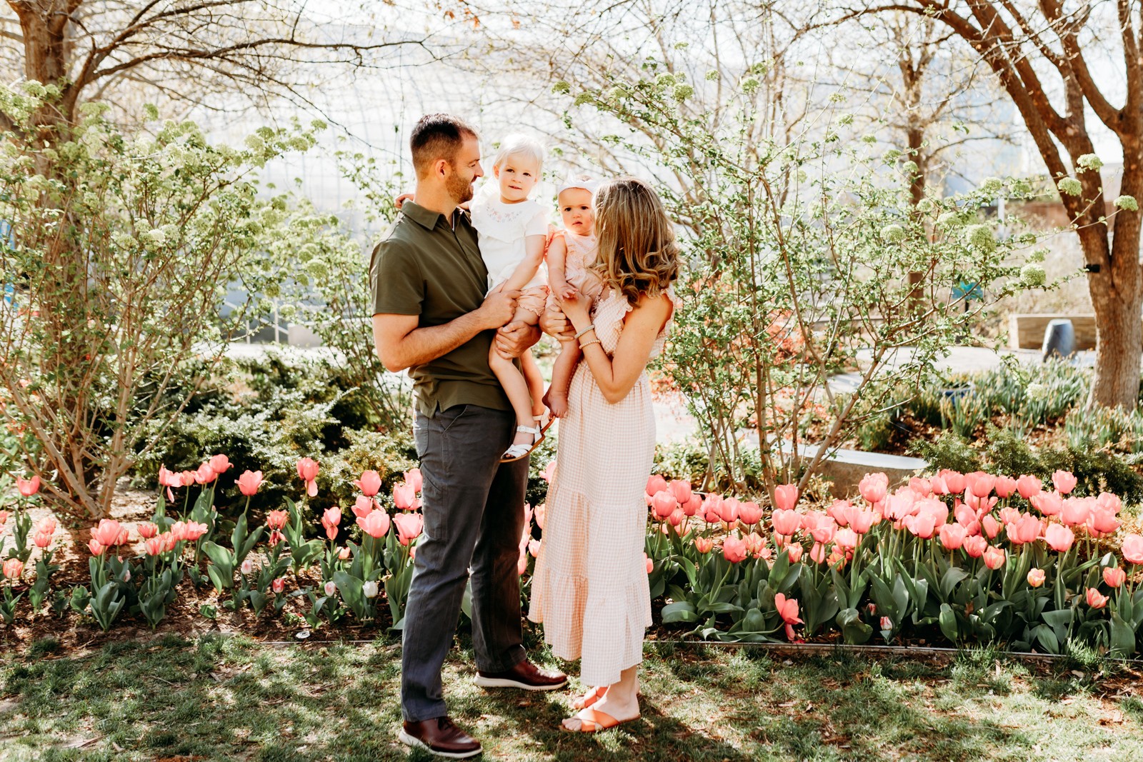 a family of 4 stands in the tulips in Myriad Gardens in downtown OKC during their family photo session.