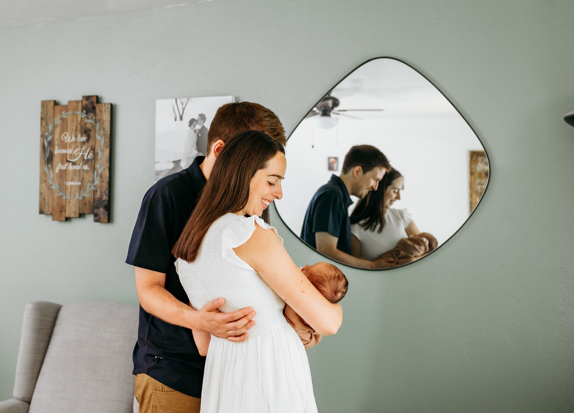 Parents hold newborn with mirror reflection during newborn photo session.