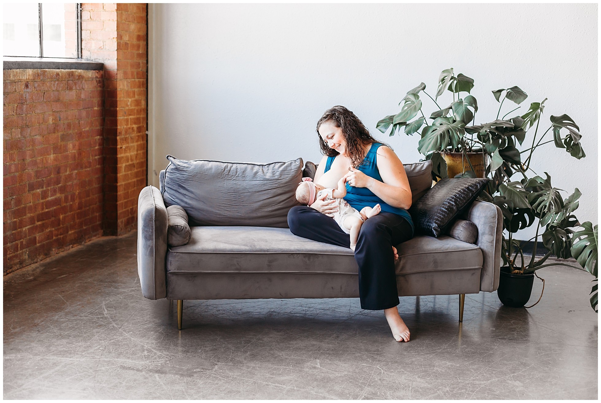 Mother nurses child on couch during OKC motherhood photo session.