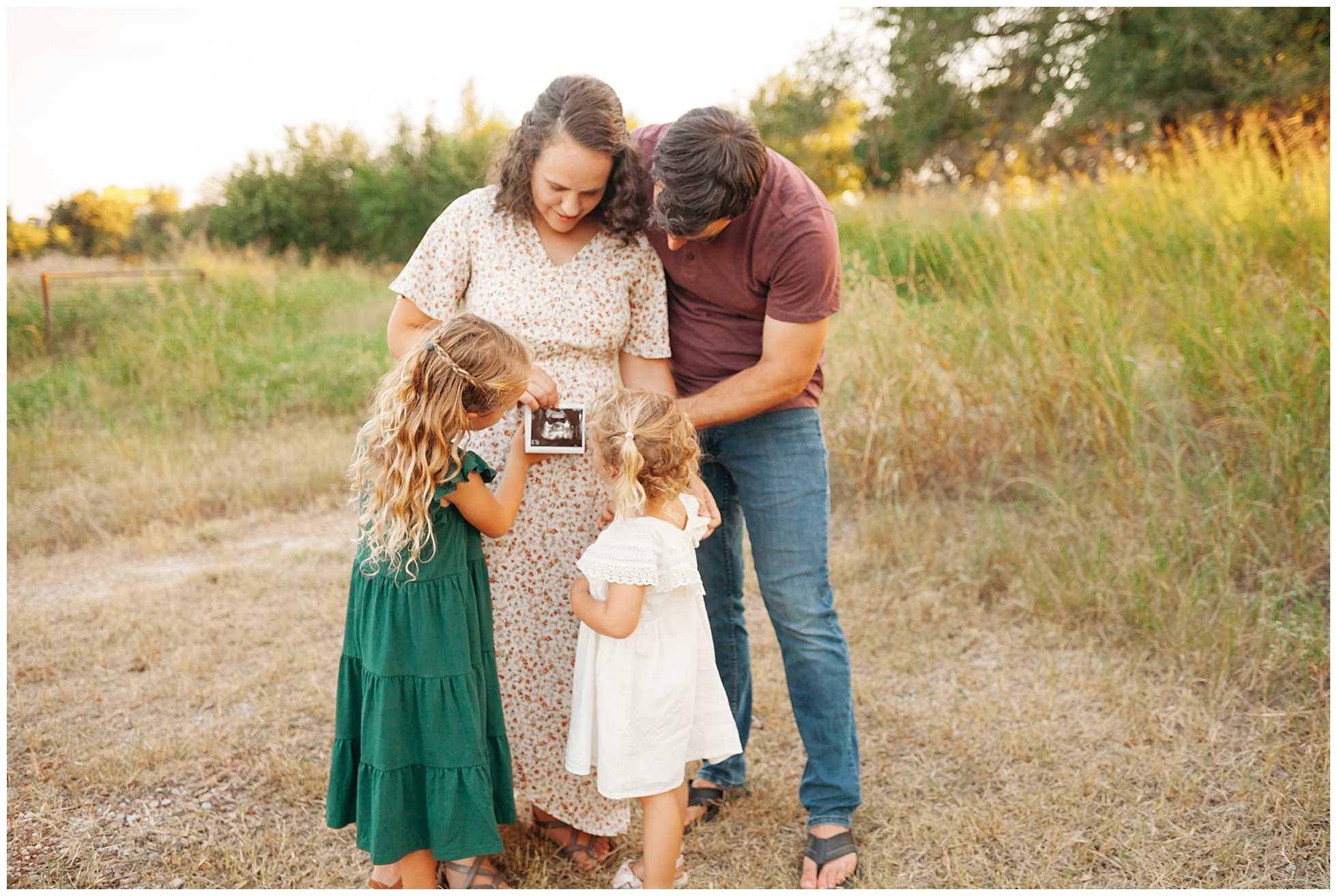 Family of four in field with ultrasound picture.