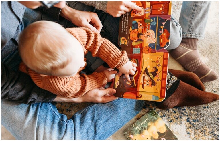 Toddler in orange shirt looks at books.