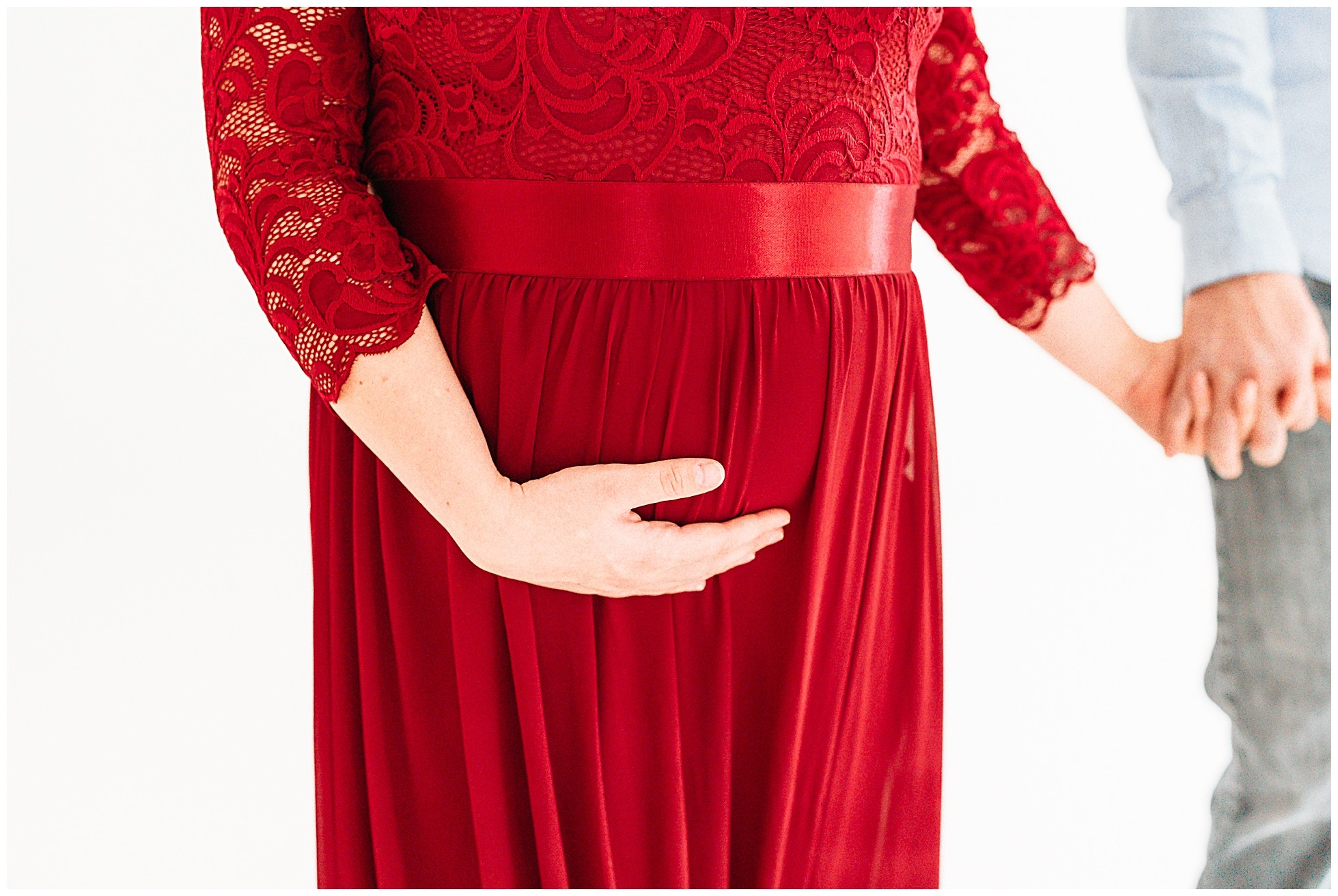 Pregnant mom in red dress holding hands with dad.